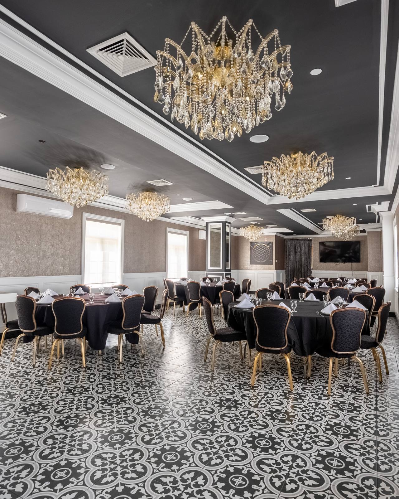 Crystal chandeliers over round tables set with black linens in The Chandelier Room