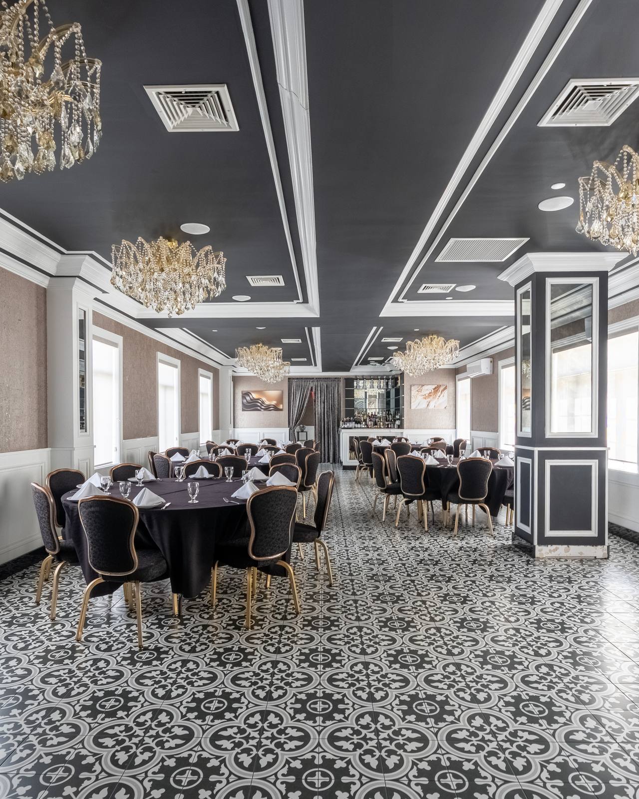Round tables and mirrored column in The Chandelier Room with coffered black ceiling
