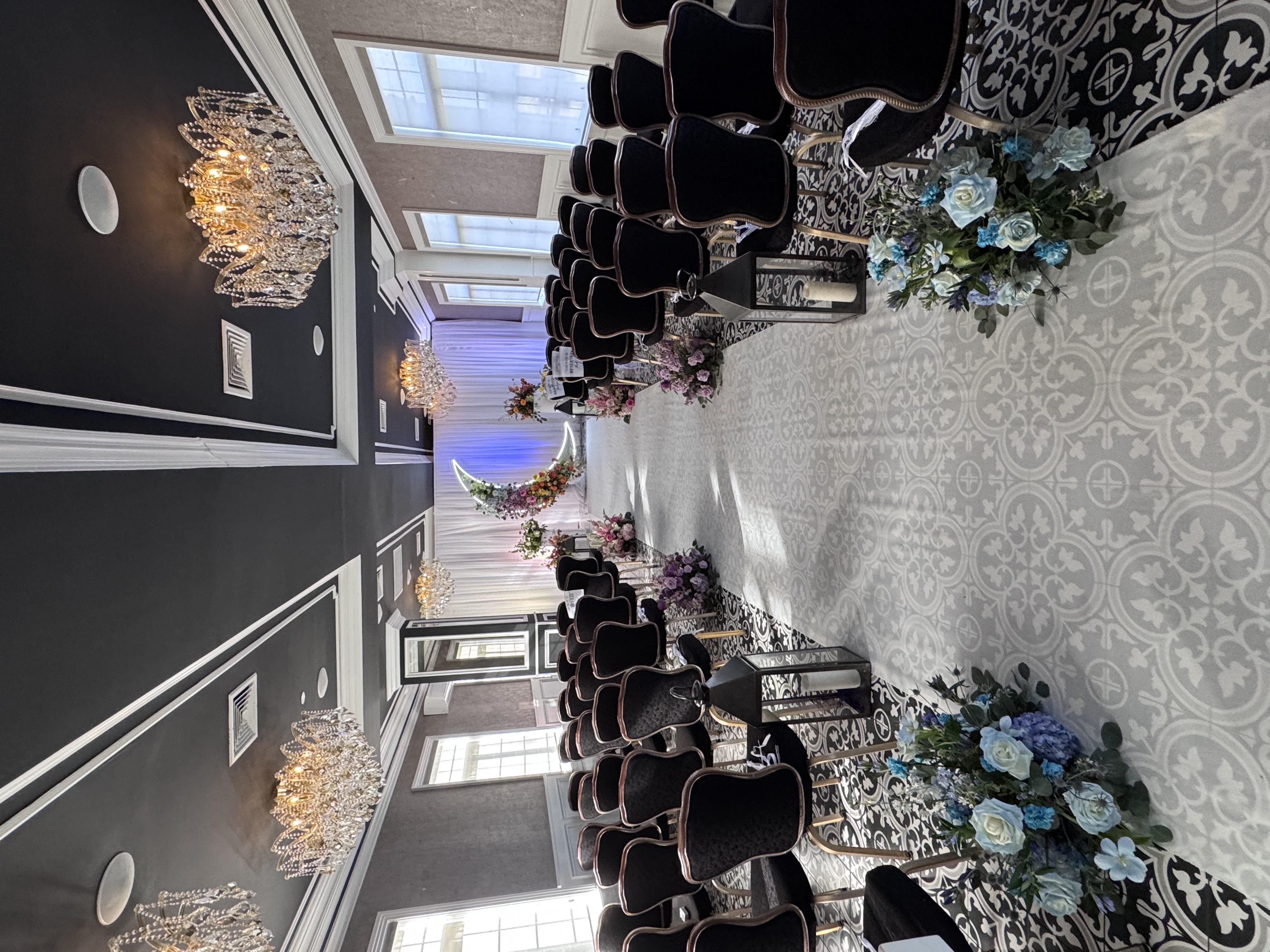 The Chandelier Room set for a ceremony with white aisle, floral moon arch and crystal chandeliers