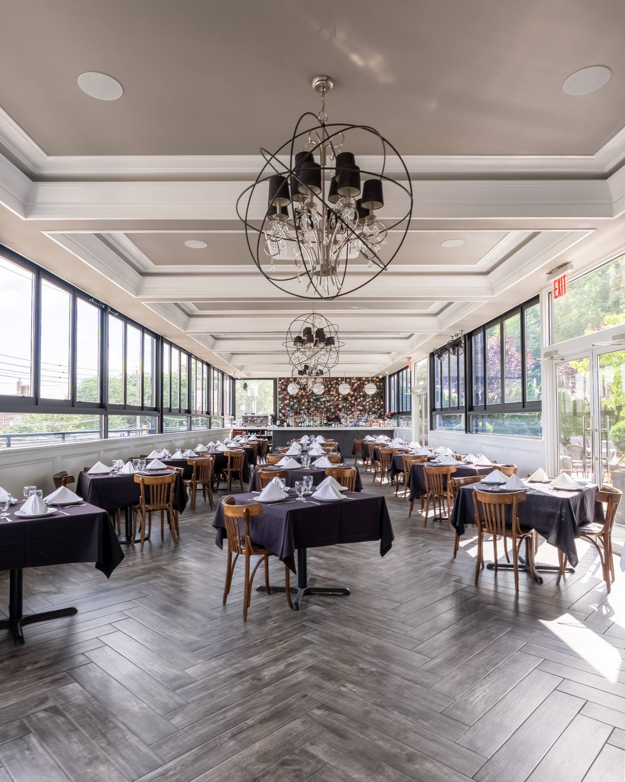 The Rooftop dining room with windows on three sides, orb chandeliers and the flower-wall bar