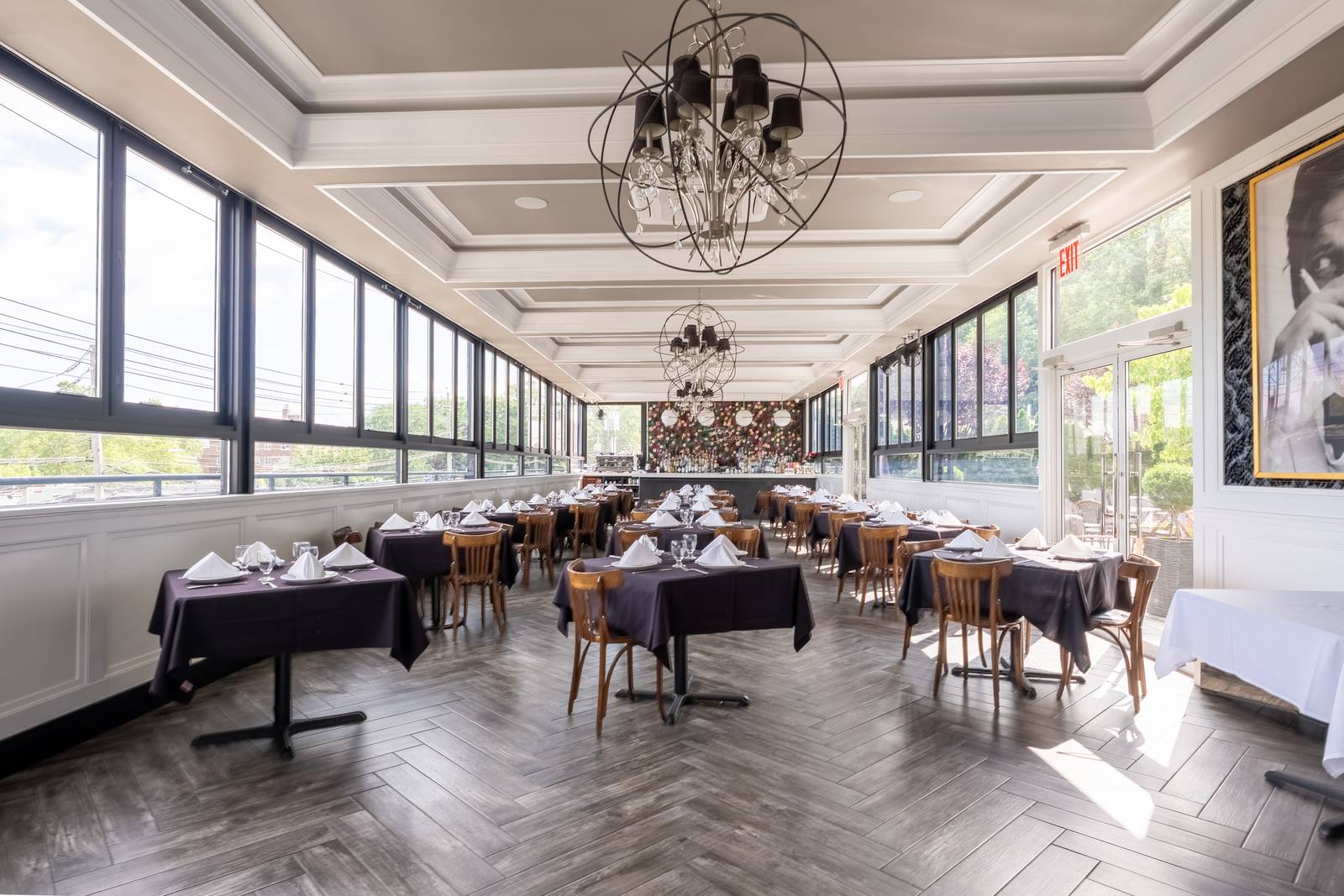 Sunlit Rooftop dining room with herringbone floors and tables dressed in dark linens