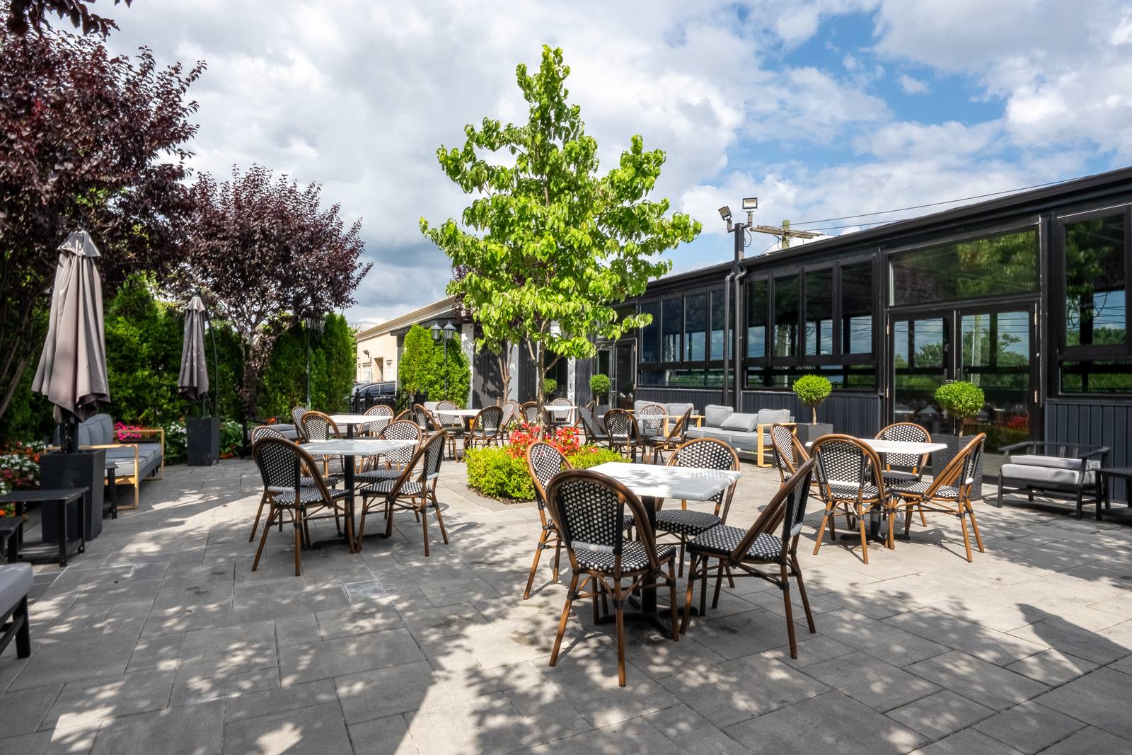 Wide view of the Rooftop patio with bistro seating, flowers and lounge corners
