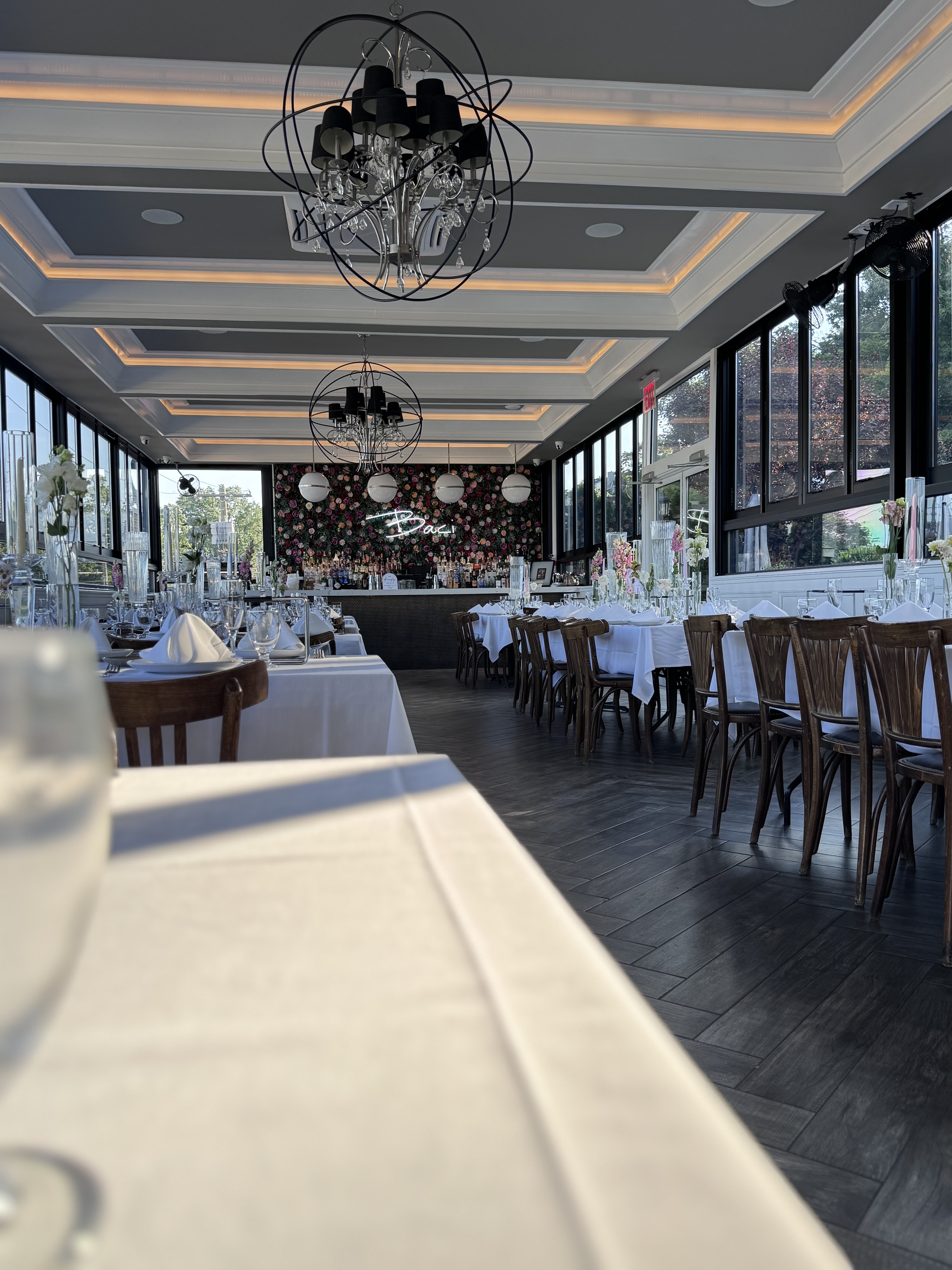 An evening celebration on The Rooftop with guests, uplighting and tall floral arrangements